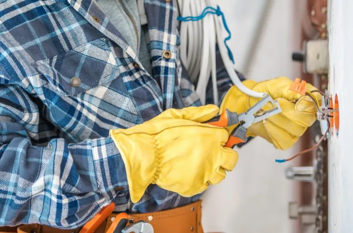 Contacto Electricista con guantes conectando el cableado de un mecanismo en la pared · Contacto