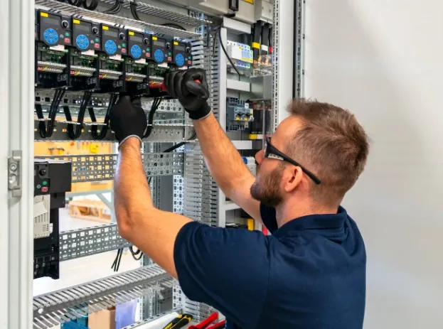 Trabajos realizados por nuestro electricista en Málaga Técnico con gafas de protección trabajando en un cuadro eléctrico de gran tamaño · Trabajos realizados por nuestro electricista en Málaga
