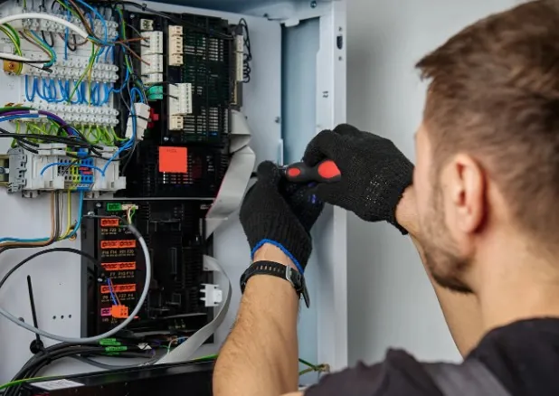 Electricista con guantes revisando el cableado de un cuadro eléctrico de vivienda · Electricista en Málaga que te lo resuelve hoy