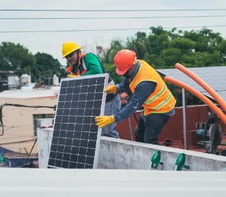 Instaladores con casco colocando un panel solar en una azotea
